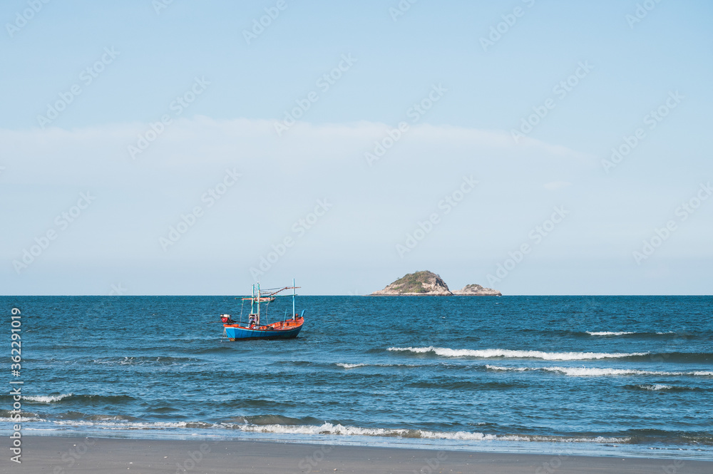 Small fishing boat is floating on the sea near the beach