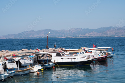 Dikili,İzmir / Turkey - July,25 2019 Boats moored on the jetty,man fishing with rod