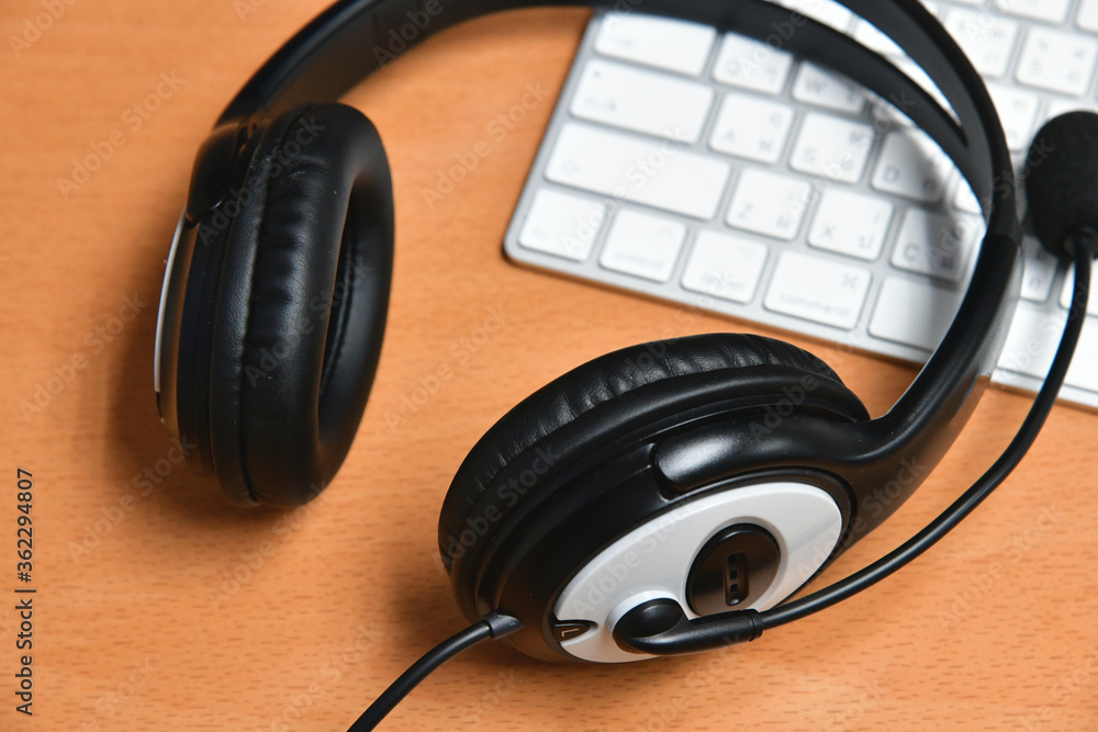 Black headset on table of technical support agent in office Black headset on table of technical support agent in office
