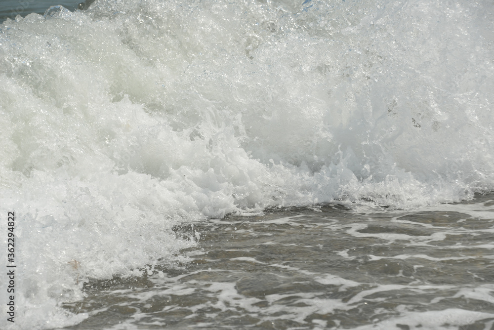 average waves on the sea reach the shore with foam and crash on the rocks with a noise average waves on the sea reach the shore with foam and crash on the rocks with a noise