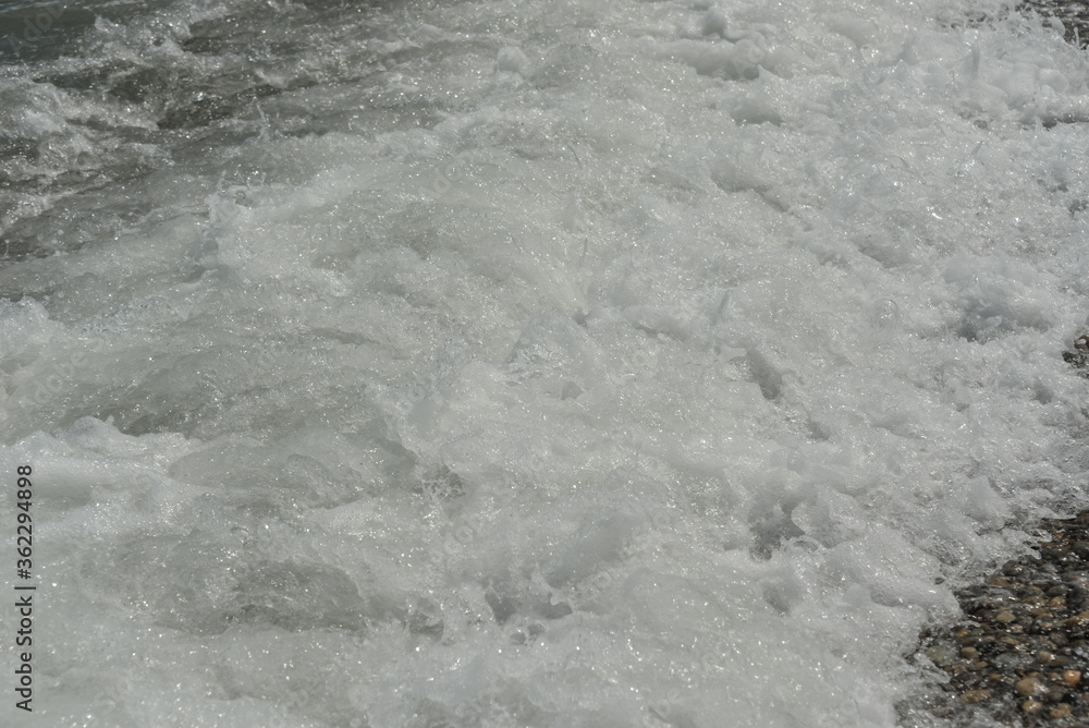 average waves on the sea reach the shore with foam and crash on the rocks with a noise average waves on the sea reach the shore with foam and crash on the rocks with a noise