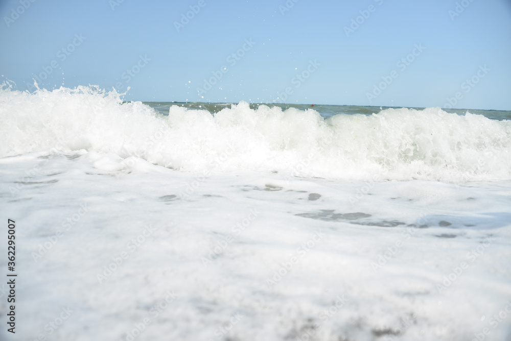 average waves on the sea reach the shore with foam and crash on the rocks with a noise average waves on the sea reach the shore with foam and crash on the rocks with a noise