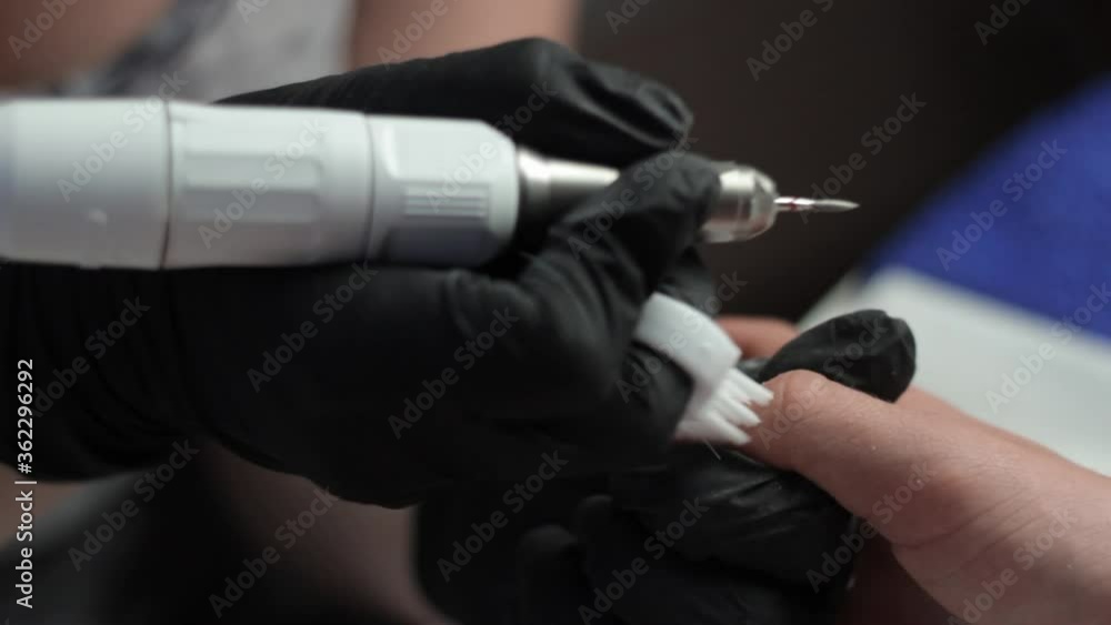 Manicurist wearing gloves using a spinning tool to push back cuticles for a client Stock Video