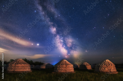 Under the bright Milky Way  Mongolia yurts on the grassland are scattered.
