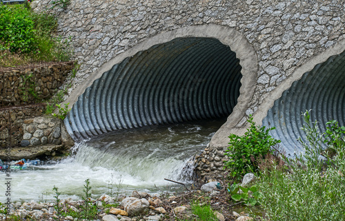 Water drains through pipes, under a bridge.