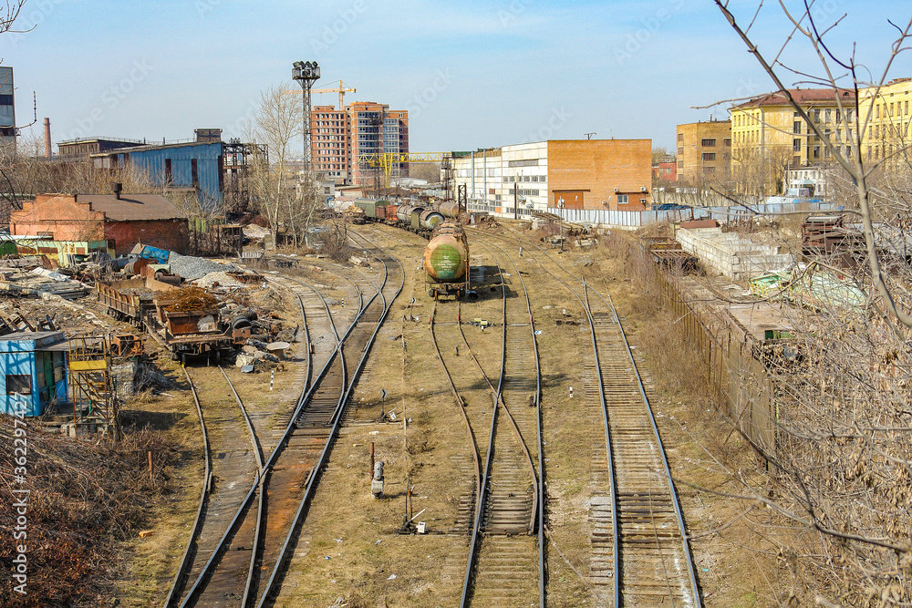 An old railway junction with numerous railways in poor condition with garbage and rust. Composition with cisterns and loading platforms