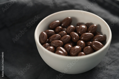 Milk chocolate dragee in white bowl on linen background © GCapture