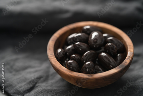 Quadro su tela Dark chocolate dragee in olive wood bowl on linen background