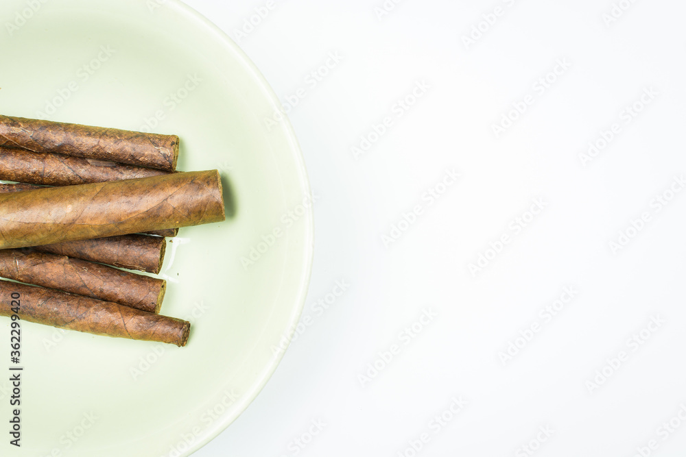 Excellent cigars from twisted sheets on plate with white background.