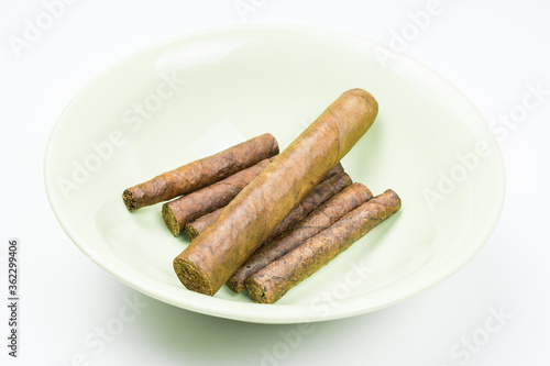 Excellent cigars from twisted sheets on plate with white background.