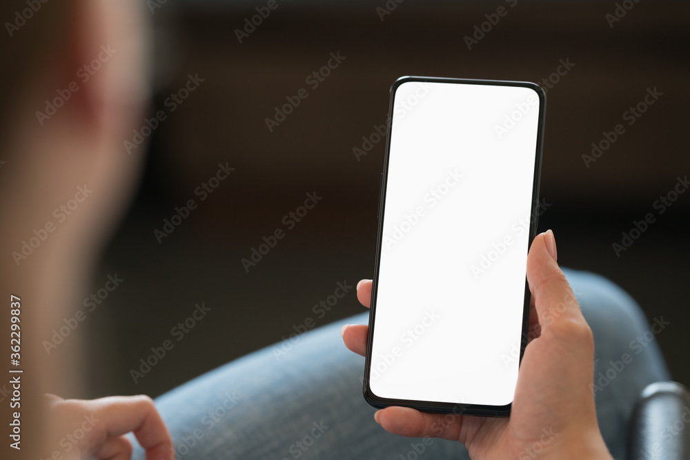 Young woman sitting in chair with modern smartphone with white screen