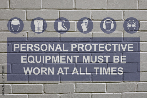 White decayed faded brick wall background with personal protection equipment must be worn at all times sign