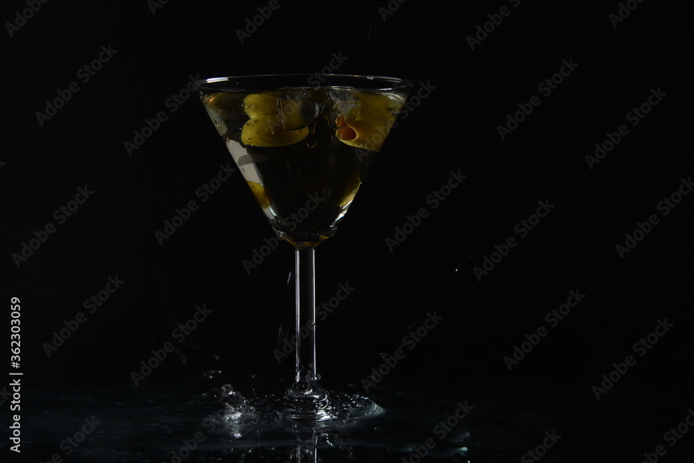 Martini with olives. Splashes near glass of cocktail. Black background Martini with olives. Splashes near glass of cocktail. Black background