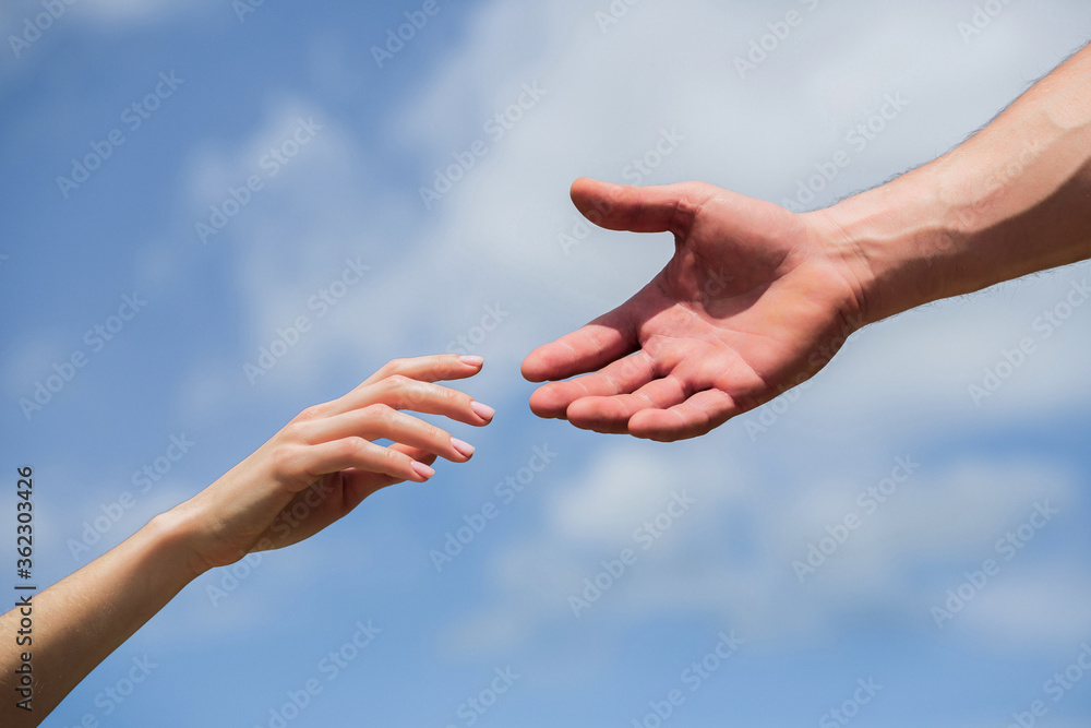 Hands of man and woman reaching to each other, support. Giving a helping hand. Hands of man and woman on blue sky background. Lending a helping hand. Solidarity, compassion, and charity, rescue Hands of man and woman reaching to each other, support. Giving a helping hand. Hands of man and woman on blue sky background. Lending a helping hand. Solidarity, compassion, and charity, rescue