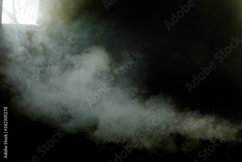 White smoke on a black background. The texture of scattered smoke in the studio. Blank for design. Layout for collages. The flash with the softbox illuminates the smoke machine.