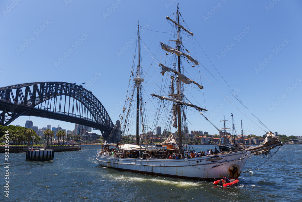 A sailing ship with tourists on board sailing at the Sydney Harbour in front of the Sydney Harbour Bridge. A sailing ship with tourists on board sailing at the Sydney Harbour in front of the Sydney Harbour Bridge.