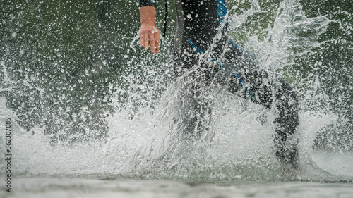 Triathlete in a wetsuit running into the lake
