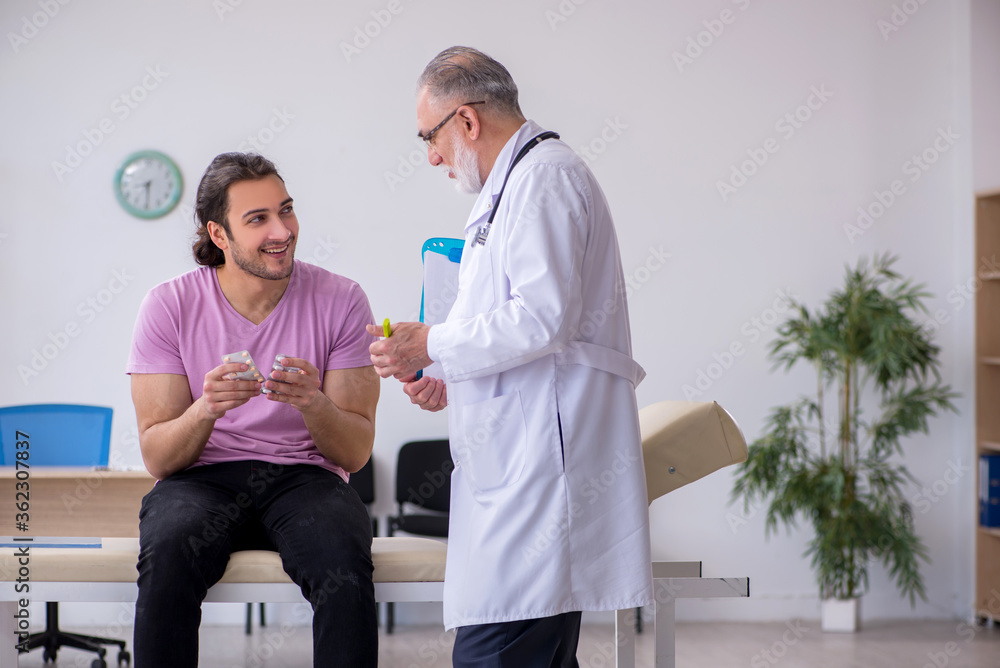 Fototapeta premium Young male patient visiting old male doctor