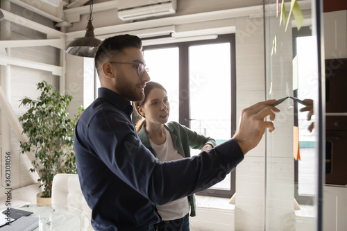 Obraz na plátně Motivated multiethnic young businesspeople write draw on board in office develop