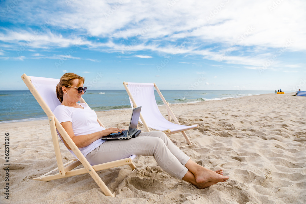 Woman using laptop on beach
