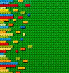 Colored toy bricks on green background