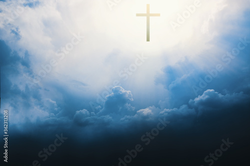 Christian cross appears bright in cloudy dark sky background