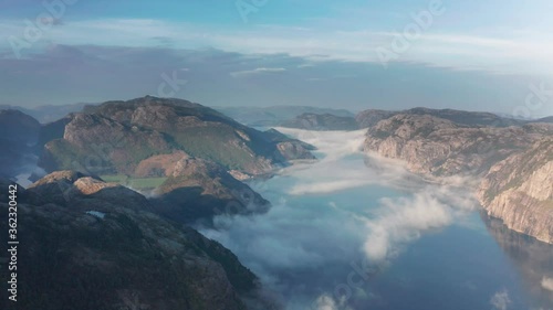 Aerial view of the famous Lysefjord. Steep cliffs rise from the calm dark blue waters. Thin ethereal wisps of clouds move in hazy air above the fjord. photo