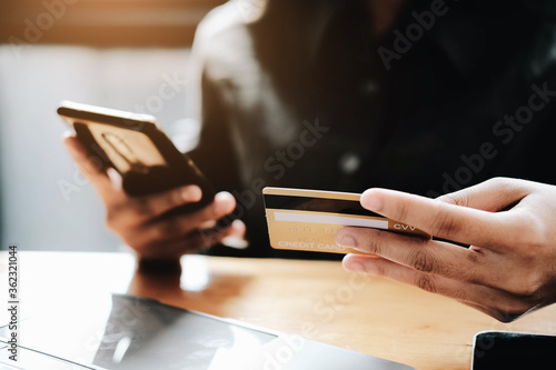 Happy young woman online shopping by credit card payment on mobile smart phone and laptop computer.