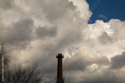 Brick boiler station with a pipe against the blue sky with white clouds