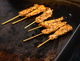 Close up of Chicken Satay cooked on a restaurant griddle