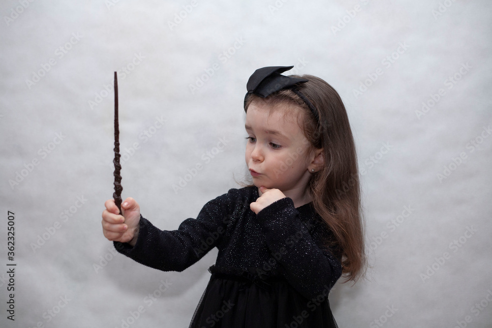 Little girl in a black dress shows a pointer on a white background. There is a place for text Little girl in a black dress shows a pointer on a white background. There is a place for text