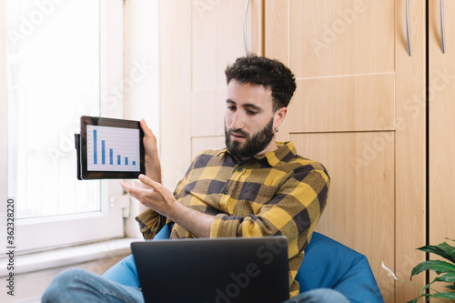 Young man making a video call while showing a graph working from home