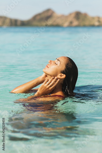 Portrait of young woman enjoying and relaxing in clean transparent ocean water. Leisure, carefree and vacation concept. Wanderlust travel in Asia.