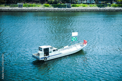 a small white boat floating on a river in Tokyo. photo