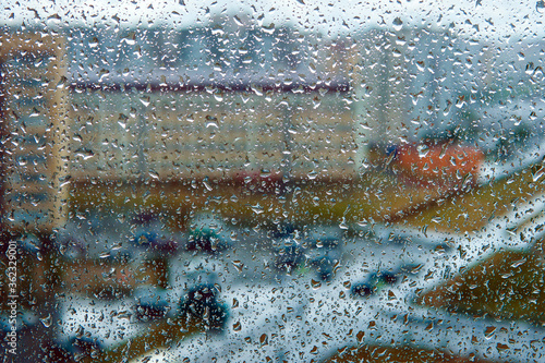 Rain falls on the surface of window panes with a cloudy background. raindrops highlighted on a cloudy background.