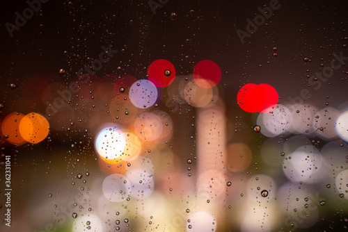 Obraz na płótnie Raindrops on the window glass at night against the background of bokeh from the lights and Windows of the houses opposite w salonie