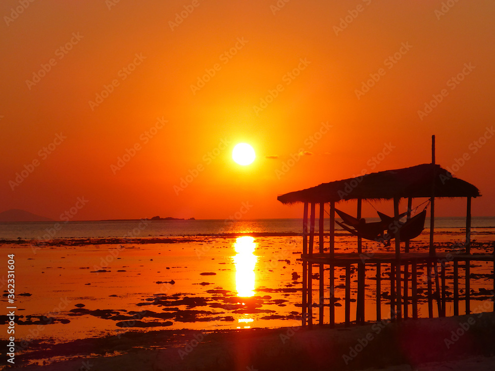 Silhouette of a cabana at sunset from Kanawa Island, Indonesia