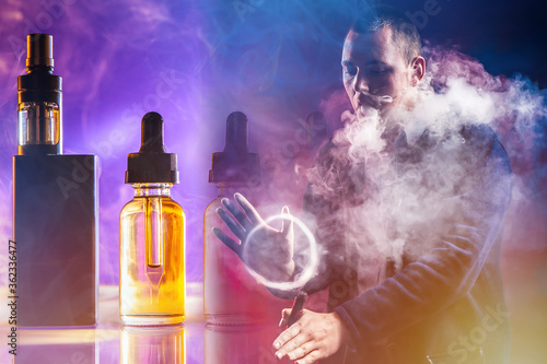The concept of vaping. A man demonstrates blowing smoke rings from an e-cigarette. VAPE accessories. VAPE shop. Smoke ring from an electronic cigarette.