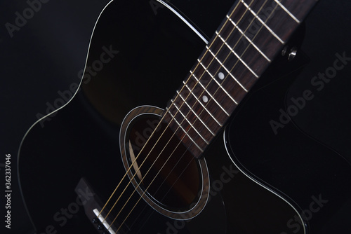 Obraz na płótnie Black acoustic guitar studio shot on black background with copyspace, Guitar is favorite music instrument for hobby. w salonie