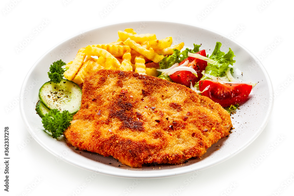 Breaded fried pork chop, French fries and vegetables on white background
