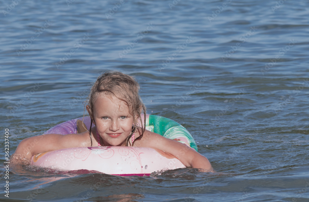 Little pretty blonde, 5 years old, European, child, girly, summer, swims in the sea on a lifebuoy, smiles, Little pretty blonde, 5 years old, European, child, girly, summer, swims in the sea on a lifebuoy, smiles,