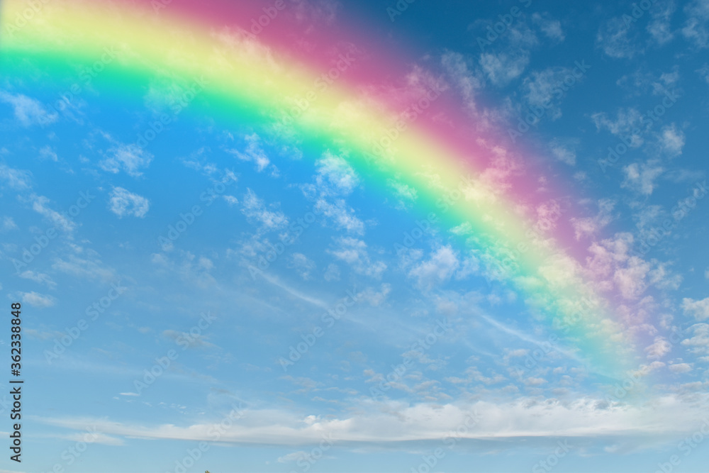 Rainbow on blue sky with white cloud background.