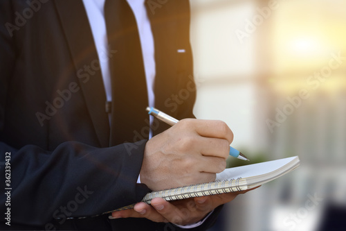 Close-up of businessman hand writing a note at business document, signing contract, partnership agreement.