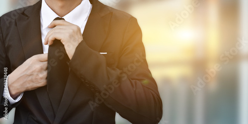 Close-up of businessman in black suit tying the necktie.