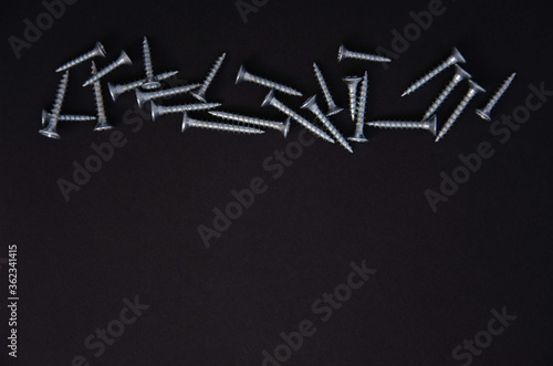 small silver metal screws on a black background
