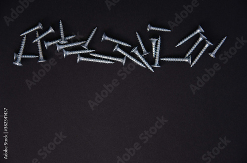 small silver metal screws on a black background