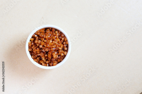 Bowl of Crystal Sugar isolated background, top view. Brown cane sugar.
