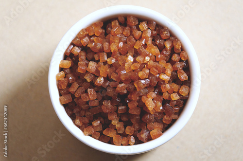 Bowl of Crystal Sugar isolated background, top view. Brown cane sugar