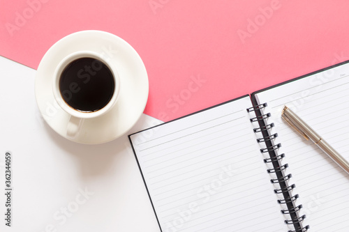 Flat lay of coffee  blank notebook and pen on split color pink and white background. Business concepts