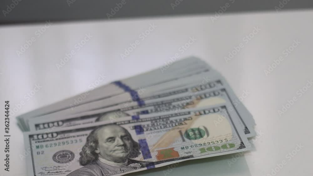 American one hundred dollar paper money pile on office desk. Concept of finance and money payment. Slow Motion view. American one hundred dollar paper money pile on office desk. Concept of finance and money payment. Slow Motion view.